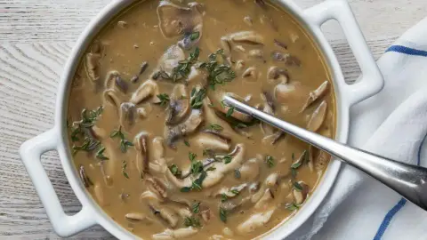 Rich vegetarian mushroom gravy with sliced mushrooms in a white serving bowl