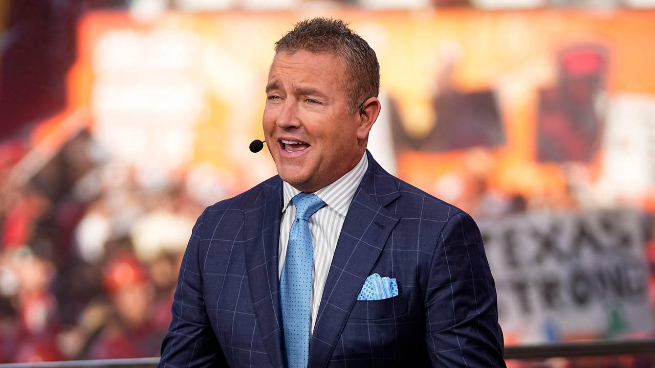 ESPN college football analyst Kirk Herbstreit speaks on a broadcast set while wearing a headset microphone