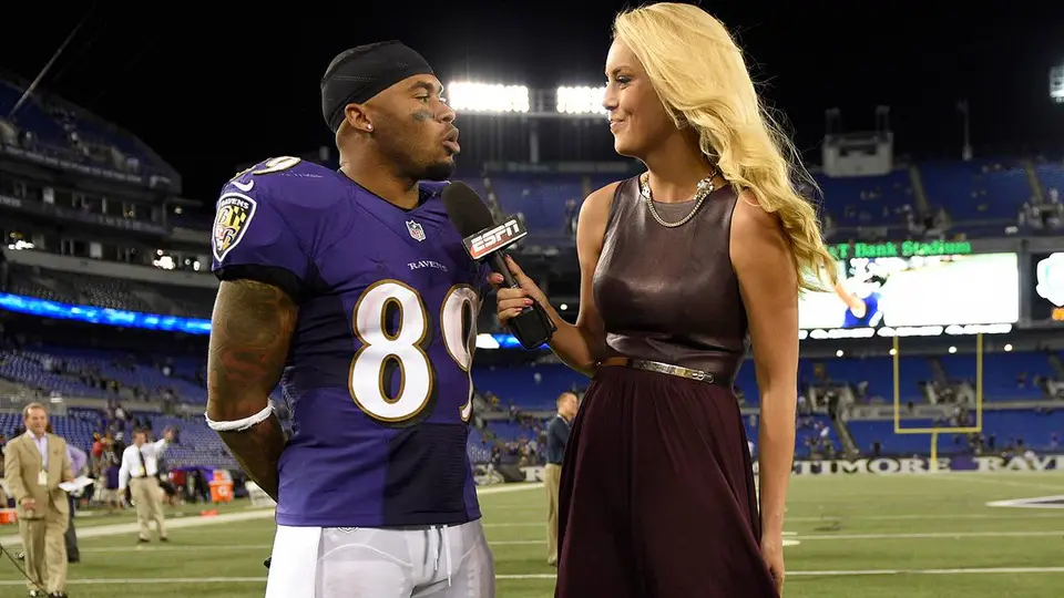 Britt McHenry holds an ESPN microphone while reporting from the sideline of a football stadium