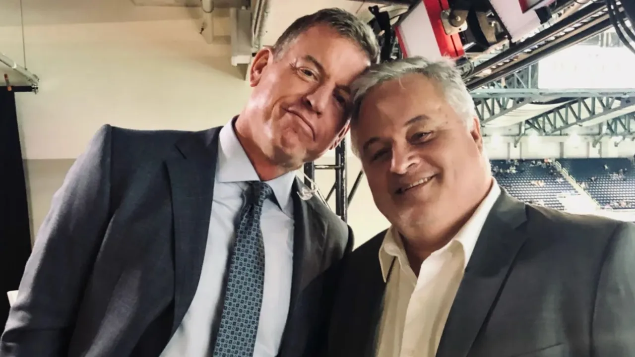 Troy Aikman and David Moulton together in a football broadcast booth.