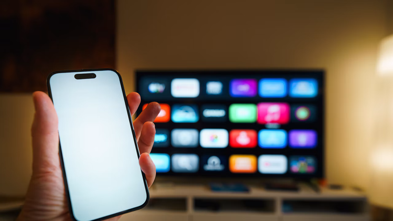 Illustrative photo of a smartphone held in front of a smart TV showing a streaming interface; it does not depict the Instagram Apple TV app.