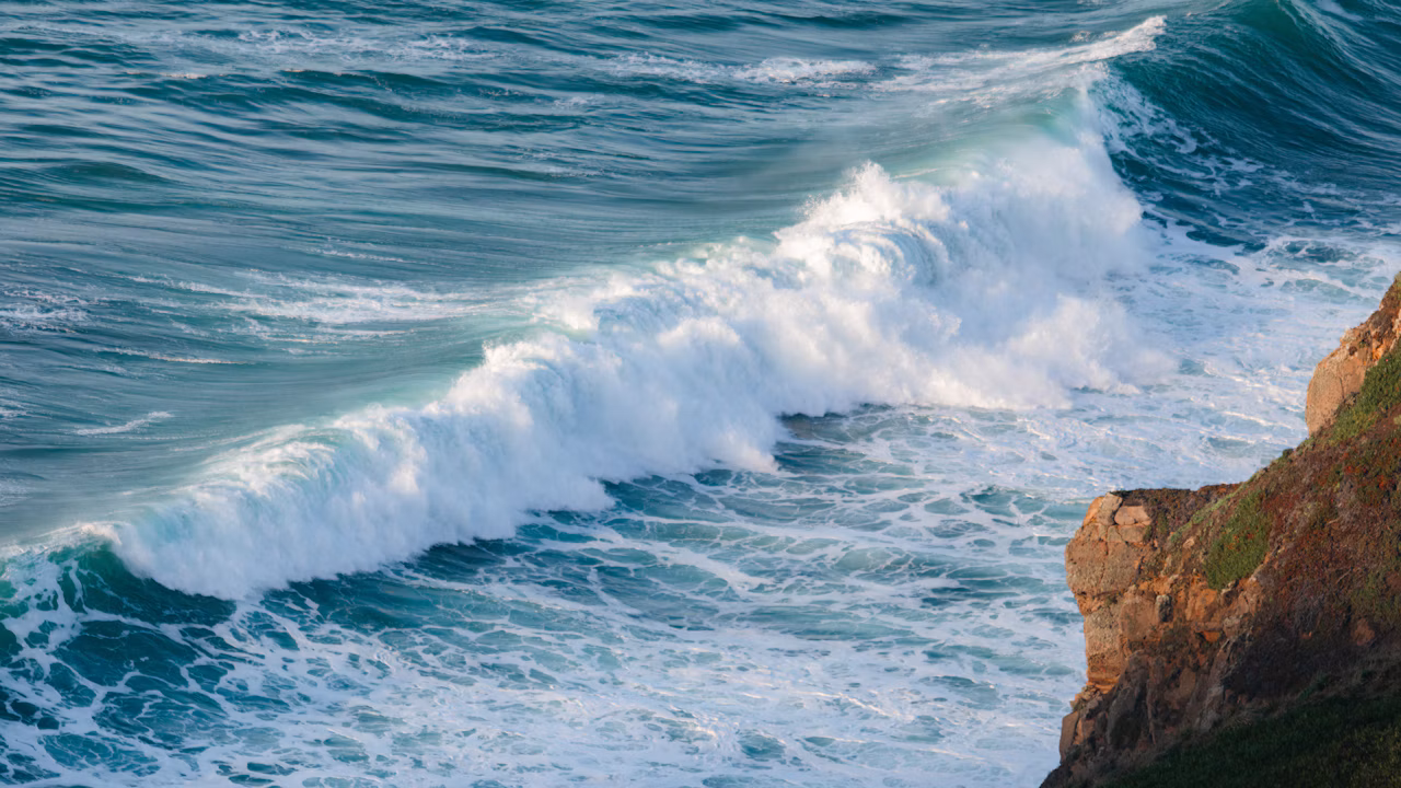 A Pacific wave crashes against a rocky cliff at Crystal Cove Beach in California.