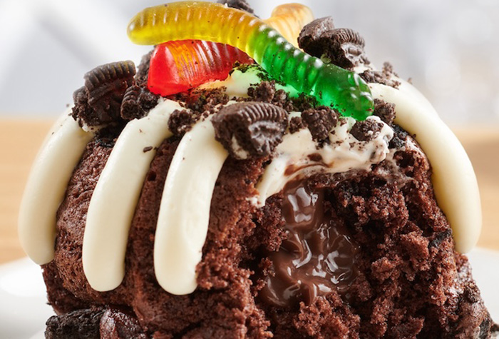 A chocolate OREO Dirt Cake Bundtlet topped with cookie crumbs and colorful gummy worms.