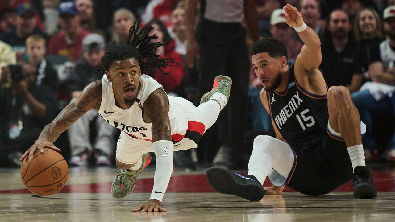 Portland Trail Blazers guard Ja Morant dives toward a loose ball in front of Phoenix Suns guard Devin Booker at Moda Center during the season opener.