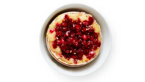Warm baked brie topped with cranberries and herbs for a holiday appetizer