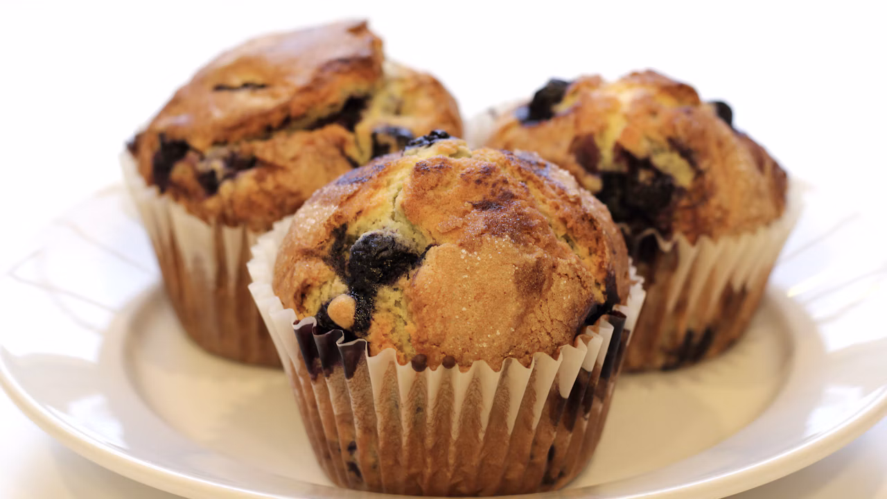 Cranberry muffins with golden tops arranged on a cooling rack