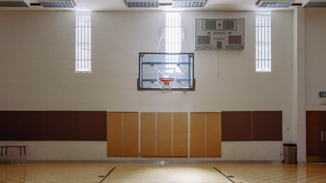 An empty indoor basketball court and hoop