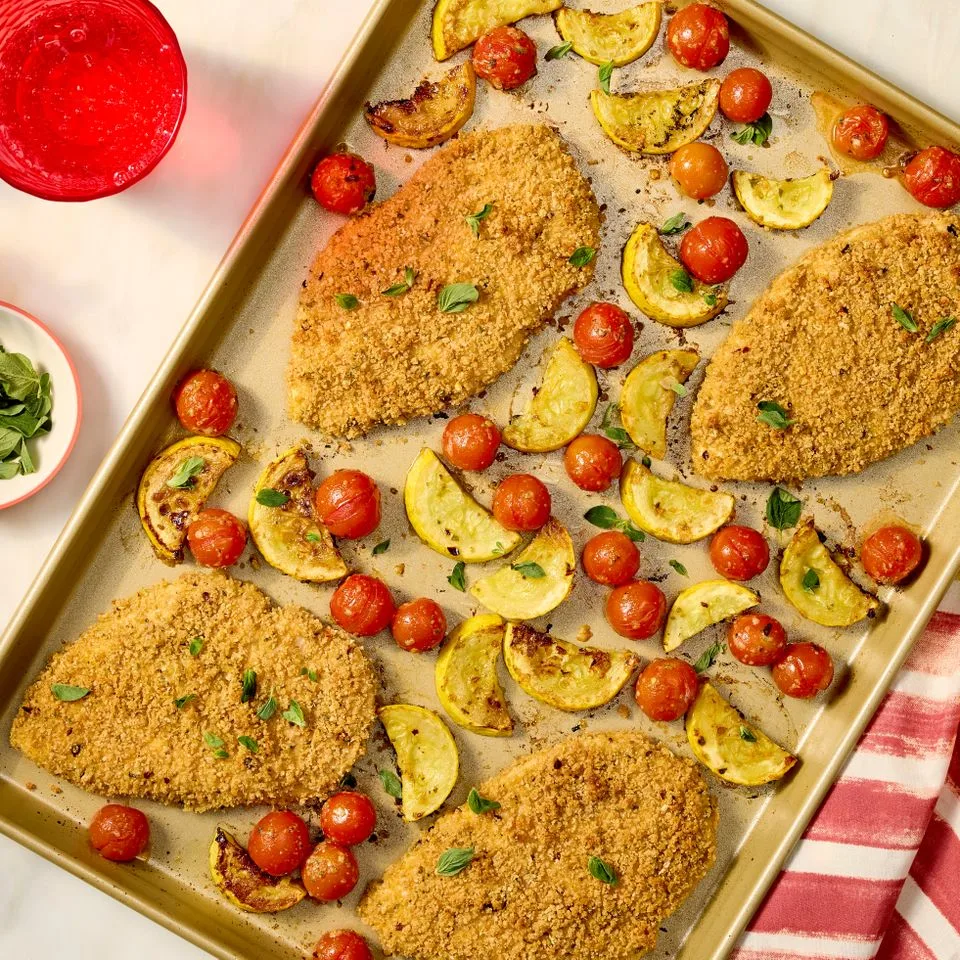 A prepared serving of crispy chicken with squash and tomatoes