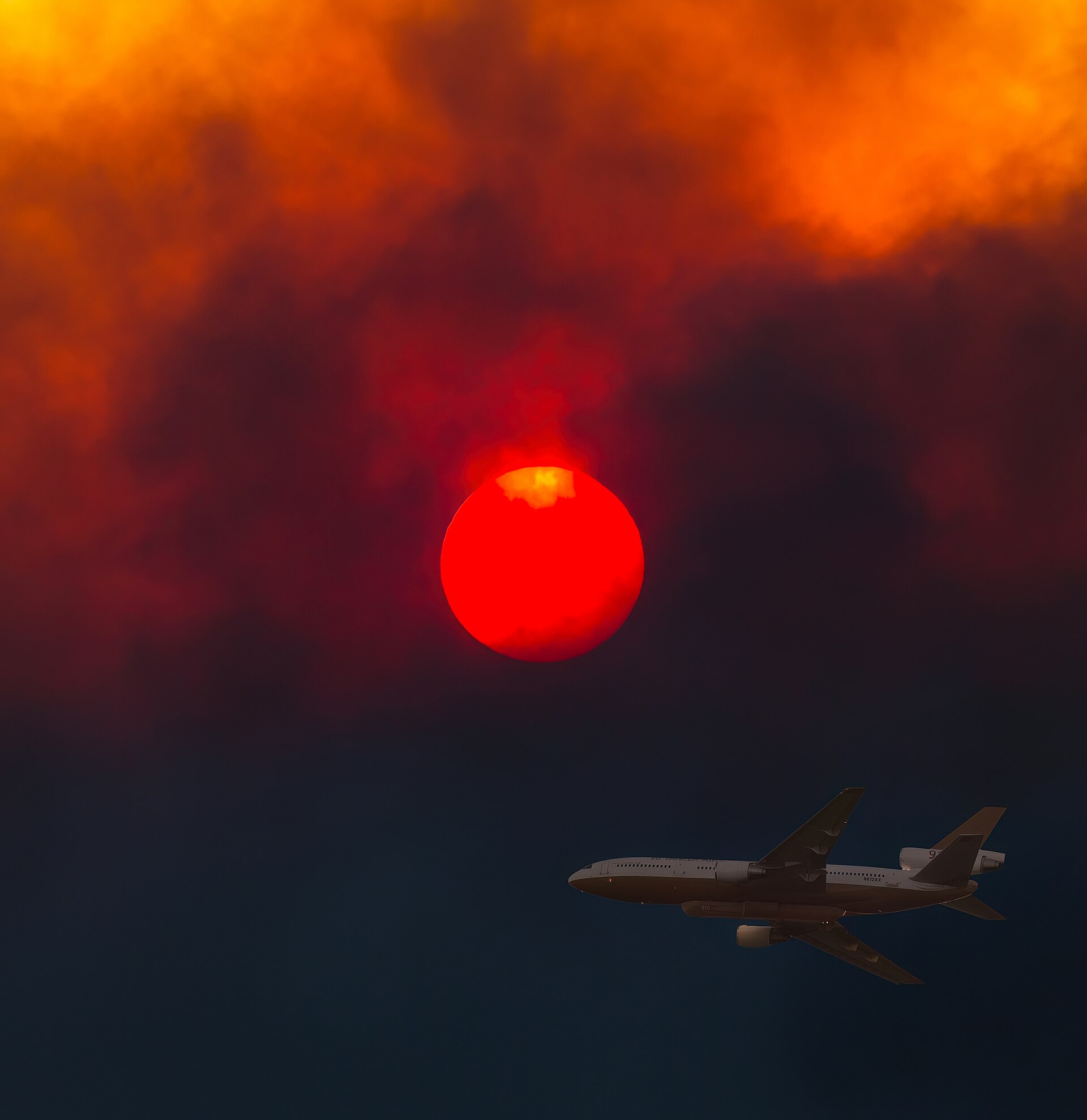 File photo of a DC-10 air tanker flying through smoke under a red sun during the 2018 Woolsey Fire in the Malibu area