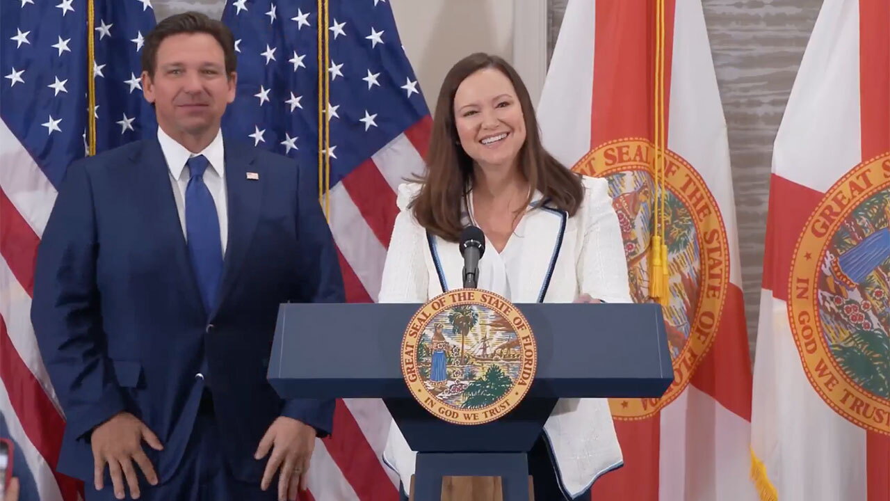 Ashley Moody speaks at a podium with Florida and United States flags behind her during her 2025 Senate appointment announcement.