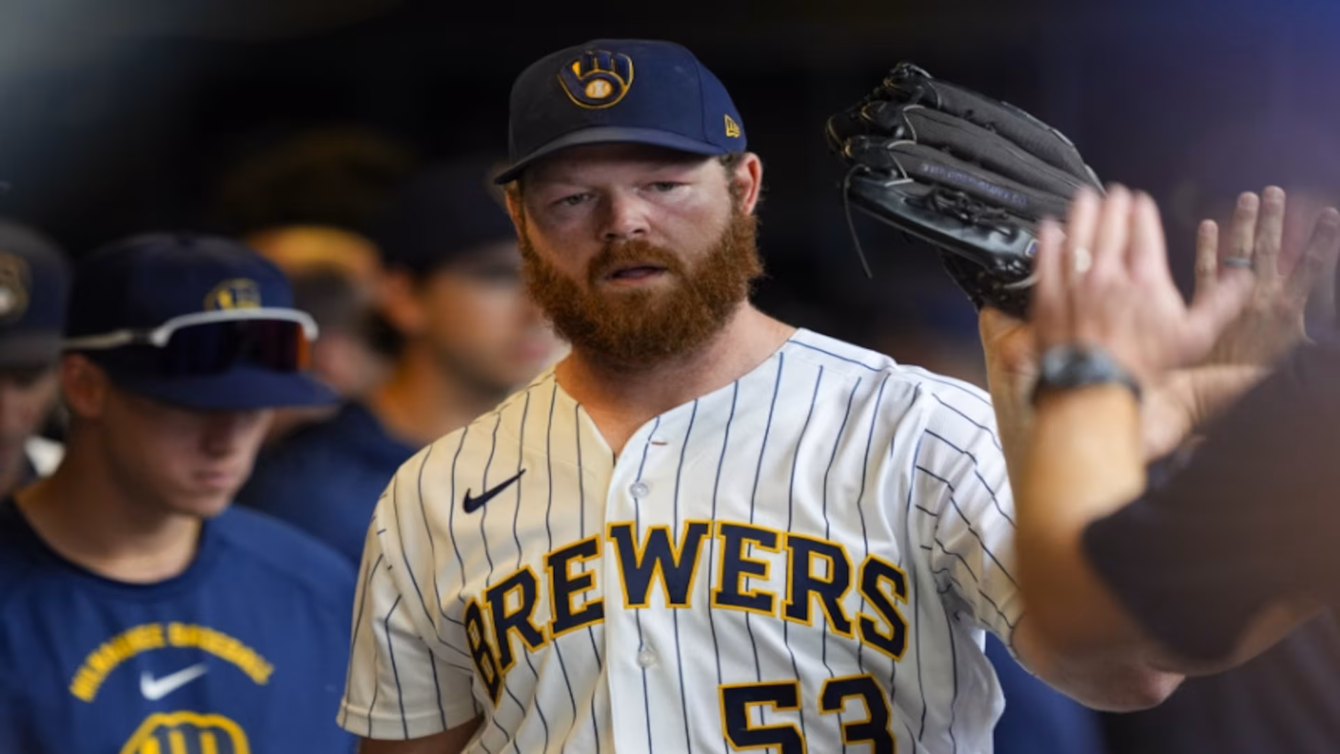 Milwaukee Brewers pitcher Brandon Woodruff high-fives teammates in the dugout during a June 2026 game against the Chicago Cubs
