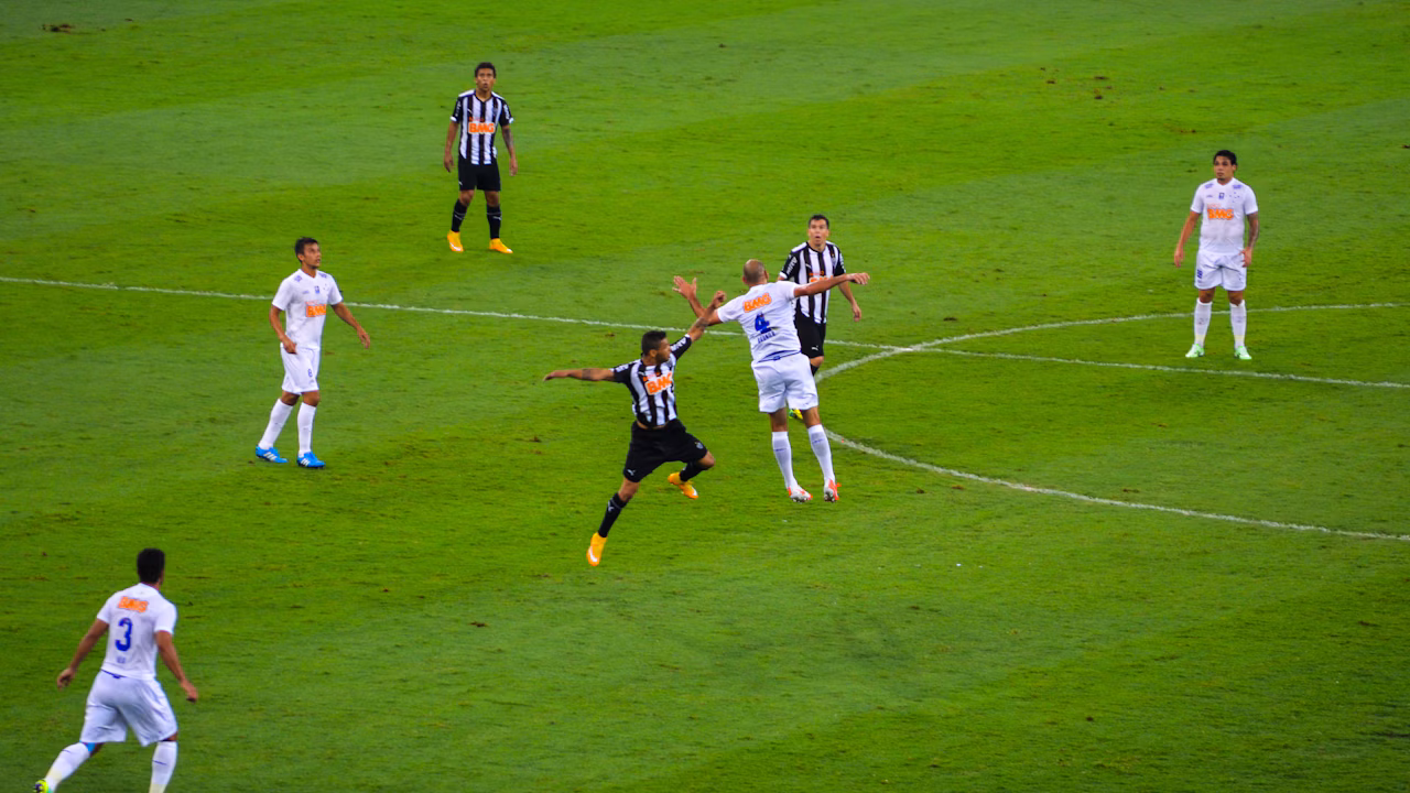 Players contest an aerial ball during a football match.