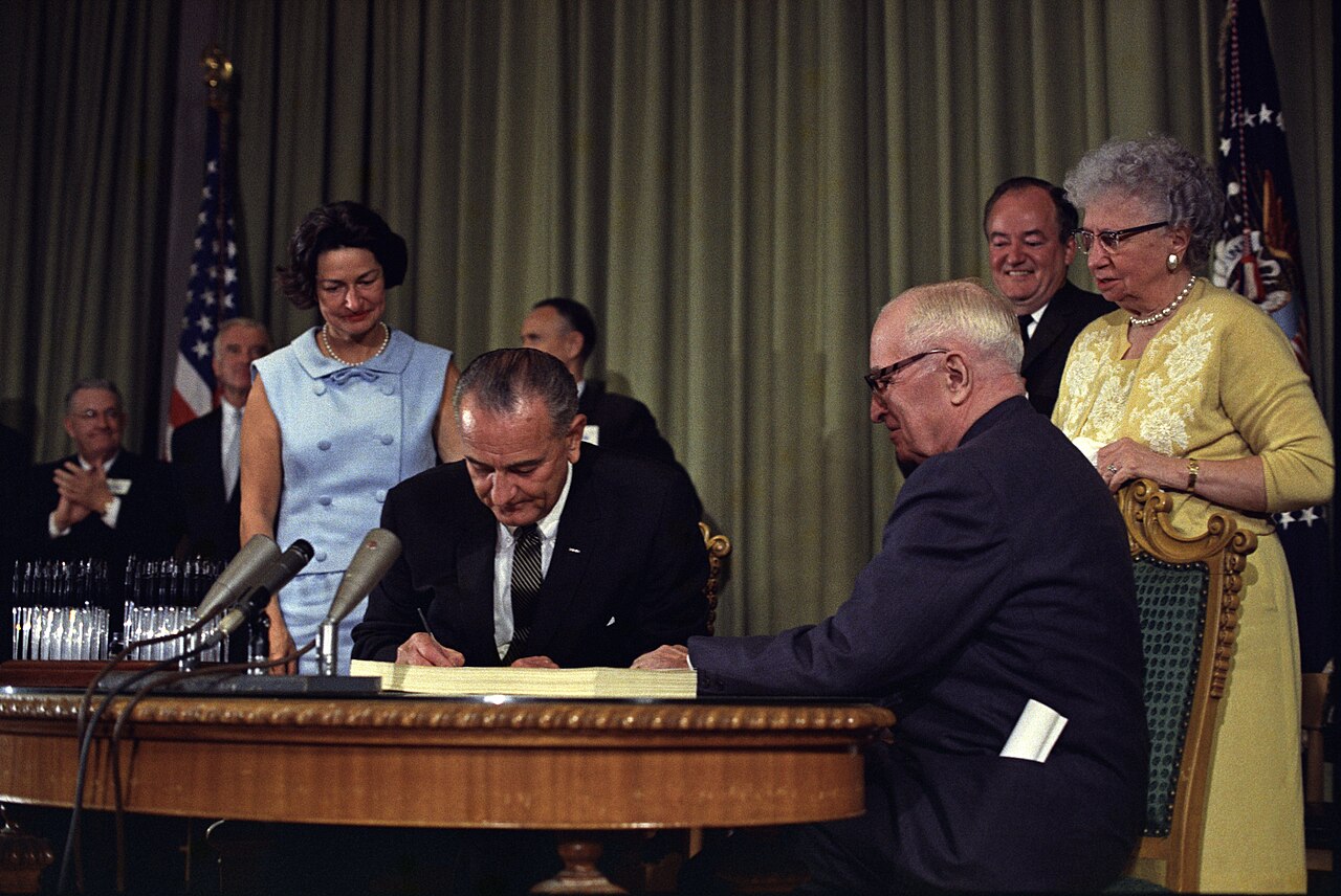 President Lyndon Johnson signing the Medicare bill in 1965 with former President Harry Truman seated beside him