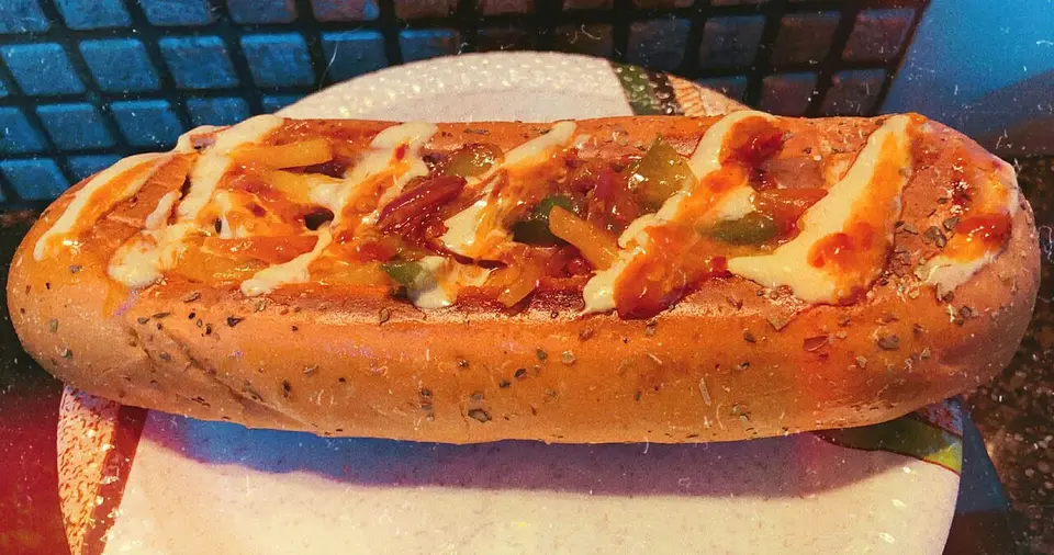 A grilled hot dog in a bun with toppings on a plate