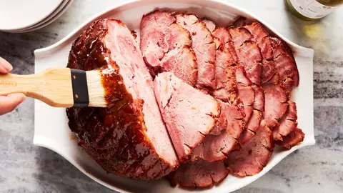 Brown-sugar glazed spiral ham on a serving platter with a glossy caramelized crust