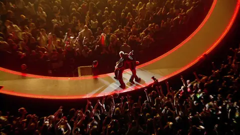U2 performs live on a circular stage before a crowd in Chicago.
