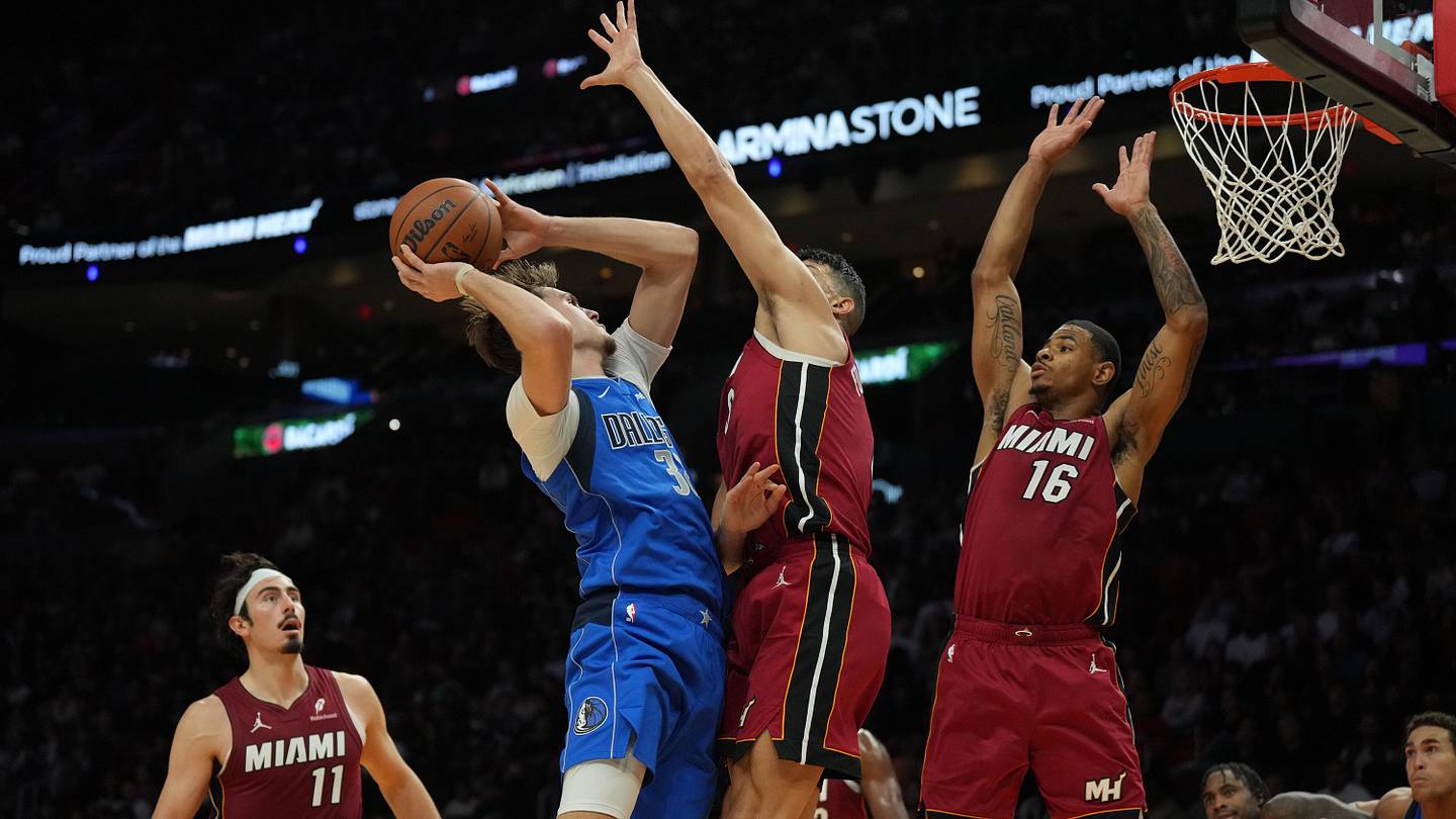A Dallas Mavericks player attacks the basket against two Miami Heat defenders during a file game at Kaseya Center