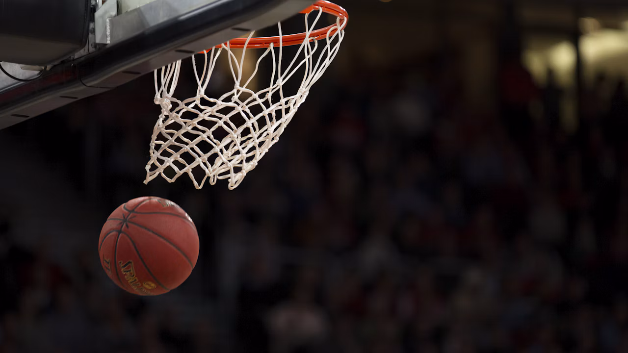 A basketball drops through the hoop during play on an indoor court