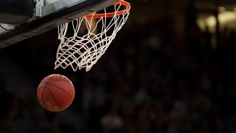 Basketball hoop and court inside a brightly lit indoor arena
