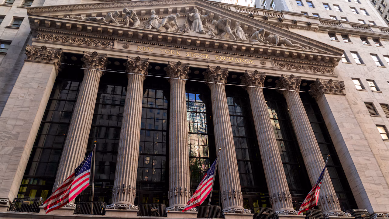The New York Stock Exchange building with American flags on Wall Street.